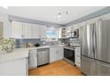 Modern kitchen with stainless steel appliances, quartz countertops, and soft gray backsplash at 10699 W 9Th Pl, Lakewood, CO 80215