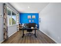Bright home office with hardwood floors, large window, and bold blue accent wall at 2144 Rosette Ln, Castle Rock, CO 80104