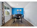 Home office with large window, blue accent wall, sleek desk, and modern decor for a comfortable work environment at 2144 Rosette Ln, Castle Rock, CO 80104