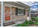 Inviting home entrance with a bright orange door, brick facade, and manicured landscaping at 11957 Claude Ct, Northglenn, CO 80233