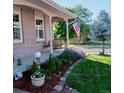 Covered front porch with a swing bench, American flag, landscaping and a charming lamp post and garden at 2190 S Uravan St, Aurora, CO 80013