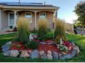 Manicured flower bed with stone border and decorative plants in front of a charming brick home with an American flag at 2190 S Uravan St, Aurora, CO 80013