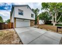 Spacious driveway leading to a two-car garage, complemented by mature trees and manicured landscaping at 3679 S Zeno Way, Aurora, CO 80013