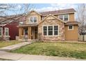 Inviting two-story home with stone accents, a cozy front porch, and a well-maintained lawn at 14214 Waterside Ln, Broomfield, CO 80023