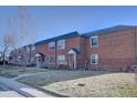 Full view of brick townhomes each with a front yard and an inviting entrance at 2870 Jasmine St, Denver, CO 80207