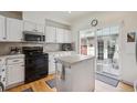 Bright kitchen features white cabinets, stainless steel appliances, and an island with tile countertops and sliding glass doors at 604 S Yarrow St, Lakewood, CO 80226