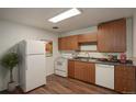 Functional kitchen with wood cabinets, white appliances, and laminate flooring at 2565 S Sheridan Blvd # 14, Lakewood, CO 80227
