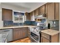 This kitchen features wood cabinets, stainless steel appliances, and dark backsplash at 15740 Sandtrap Way, Morrison, CO 80465