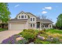 Charming two-story home with a well-manicured front yard, colorful flowers, and a covered front porch seating area at 7954 S Franklin Ct, Centennial, CO 80122