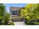 Two-story home features a stone facade, two car garage, and beautiful trees on a sunny day at 16404 E 117Th Ave, Commerce City, CO 80022