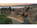 Stunning aerial view of property with circular driveway, mature trees, and distant lake views at 7382 W Stanford Ave, Littleton, CO 80123