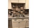 Close up of kitchen stainless steel sink, tiled backsplash and granite countertops at 2301 E Fremont Ave # W02, Centennial, CO 80122