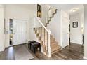 Inviting entryway with wood floors, a staircase with white railing, and natural light at 6280 Snowberry Ave, Firestone, CO 80504