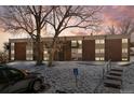 Three story brick building with brick facade, balconies, and a handicap parking sign, set against a pink sky at 3623 S Sheridan Blvd # 8, Denver, CO 80235