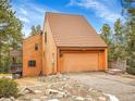 Wood-sided home boasts a large garage, private deck and inviting exterior with beautiful blue skies at 23485 Bluestem Dr, Golden, CO 80401