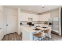 Modern kitchen with white cabinets, stainless steel appliances, and a central island with seating at 495 Bennett Ave, Bennett, CO 80102