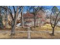 Brick home with tile roof, mature trees, and a black metal fence at 1650 Monaco St Pkwy, Denver, CO 80220