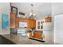 Well-lit kitchen featuring granite counters, wood cabinets, and modern appliances at 6468 S Hudson St, Centennial, CO 80121