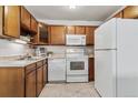 Cozy kitchen featuring wood cabinets, white appliances, and tile flooring at 9155 E Center Ave # 3C, Denver, CO 80247