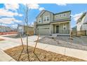 Two-story home with green siding, a stone chimney accent, and an attached two-car garage at 9293 Biscay St, Commerce City, CO 80022