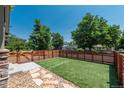Spacious backyard featuring an artificial lawn, stone walkway and modern horizontal wood fence at 915 N Kearney St, Denver, CO 80220