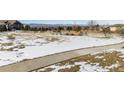 Snowy front yard with mountain views and a walkway leading to the house at 997 Brocade Dr, Highlands Ranch, CO 80126