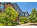 Inviting townhome with brick and gray siding, complemented by lush greenery and a well-kept lawn at 4885 S Algonquian Way, Aurora, CO 80016