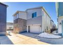 Rear of home showcasing a two-car garage with a modern glass panel door and a concrete driveway at 23970 E 41St Ave, Aurora, CO 80019