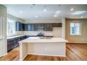 Bright kitchen with center island, dark cabinets, stainless appliances, and a white subway tile backsplash at 23970 E 41St Ave, Aurora, CO 80019