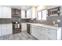 Modern kitchen features stainless steel appliances, white cabinetry, granite countertops, and farmhouse sink at 2055 Quail Dr, Lakewood, CO 80215