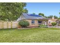 Exterior view of well-maintained home showcasing solar panels, fenced yard, and landscaped lawn at 6995 W 27Th Ave, Wheat Ridge, CO 80033