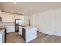 Contemporary kitchen featuring stainless steel appliances, white cabinetry, and a kitchen island at 728 N Bently St, Watkins, CO 80137