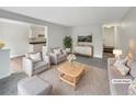 Staged living room with modern furniture, decor, and view of the kitchen at 9976 Appletree Pl, Thornton, CO 80260