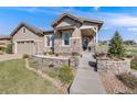 Charming home featuring stone accents, a covered porch, manicured landscaping, and inviting curb appeal at 360 Basilwood Way, Highlands Ranch, CO 80126