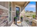Welcoming front porch featuring stone accents, decorative plants, and a stylish front door with neighborhood views at 360 Basilwood Way, Highlands Ranch, CO 80126