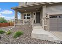 Inviting front porch with stone accents, a gray front door, and a well-maintained yard at 13205 E 109Th Ave, Commerce City, CO 80022