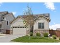 Charming home with a stone and siding exterior, solar panels, an attached garage, and a well-manicured lawn at 756 Ranchhand Dr, Berthoud, CO 80513