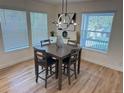 Dining area features a modern chandelier, a wood table, and lots of light from the three windows at 3866 S King St, Denver, CO 80236