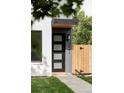 A modern, black front door with glass panels, complemented by a sleek awning and manicured lawn at 1543 Glencoe St, Denver, CO 80220