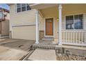 Inviting front porch with white railings, a wood door, and an attached two-car garage at 5423 Ben Park Cir, Parker, CO 80134