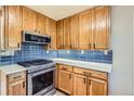 Updated kitchen with wooden cabinets, sleek countertops, and stainless steel oven and microwave at 3224 Troy St, Aurora, CO 80011