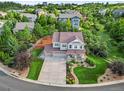Aerial view of a beautiful two-story home with a three car garage surrounded by lush landscaping and mature trees at 2384 Crestridge Dr, Castle Rock, CO 80104