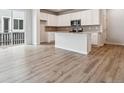 Bright kitchen featuring white cabinets, a large island, stainless steel appliances, and wood-look floors at 14149 Deertrack Ln, Parker, CO 80134