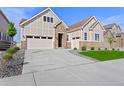 Two-story house with stone and beige siding, a three-car garage, and a landscaped lawn at 7033 S Waterloo Way, Aurora, CO 80016
