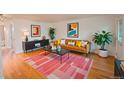 A stylish living room with hardwood floors, modern decor, a cozy tan leather sofa, and brightly colored artwork at 558 N Washington St # 103, Denver, CO 80203