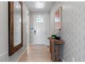 Welcoming entryway with a light wood floor, stylish wood table, mirror and attractive wall paper at 3456 Recess Ln, Castle Rock, CO 80108