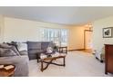 Bright living room with large windows, comfortable sofa, and a view into the open-concept home at 7926 S Corona Ct, Centennial, CO 80122