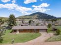 Ranch-style home on a grassy lot with mature trees and scenic mountain views at 26063 Morris Ave, Conifer, CO 80433