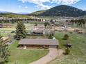 Aerial view of home situated on a green lot with other houses nearby and mountain views at 26063 Morris Ave, Conifer, CO 80433