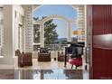 Elegant living room with a piano, plush seating, and a large arched window framing stunning mountain views at 814 Neville Ln, Golden, CO 80401
